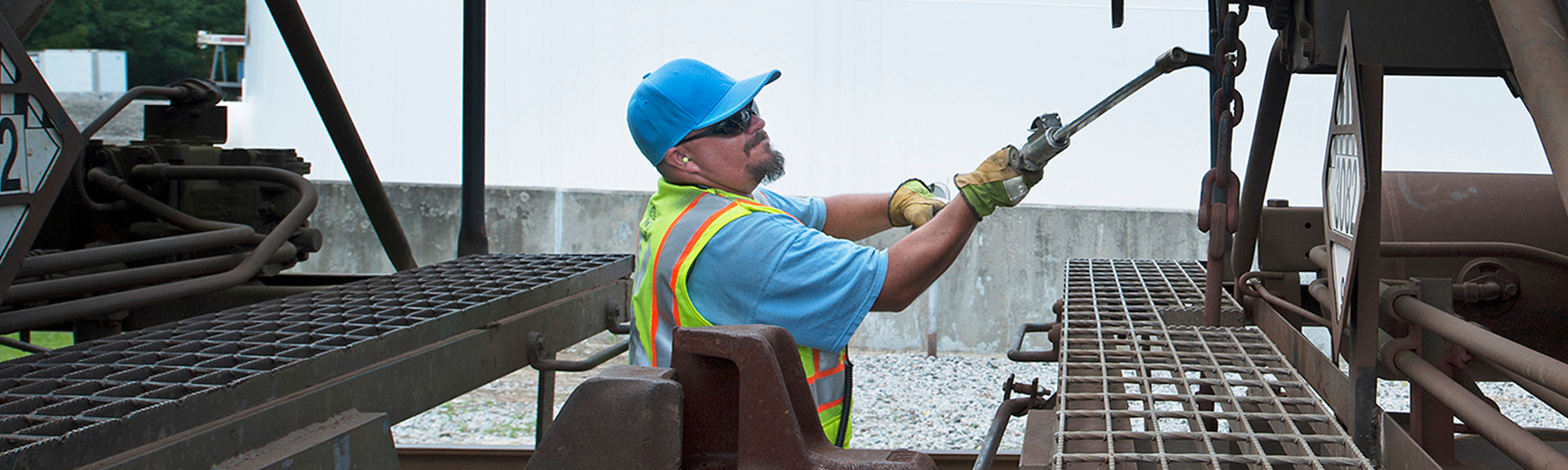 G&W employee wearing a safety vest, cap, and sunglasses while using a tool that is hooking onto a chain