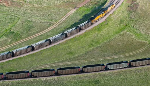Aerial view of a train pulling freight cars in a grassy landscape