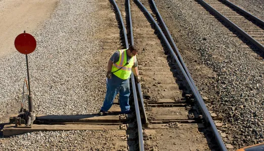G&W employee wearing a high-visibility vest and inspecting railcar tracks