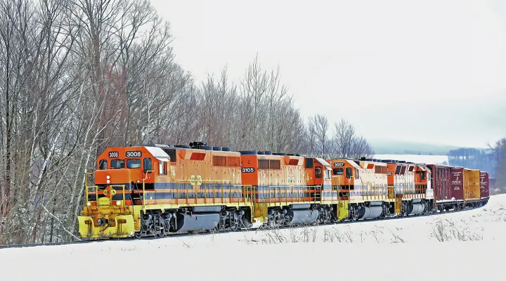 Train pulling freight railcars in a snowy landscape