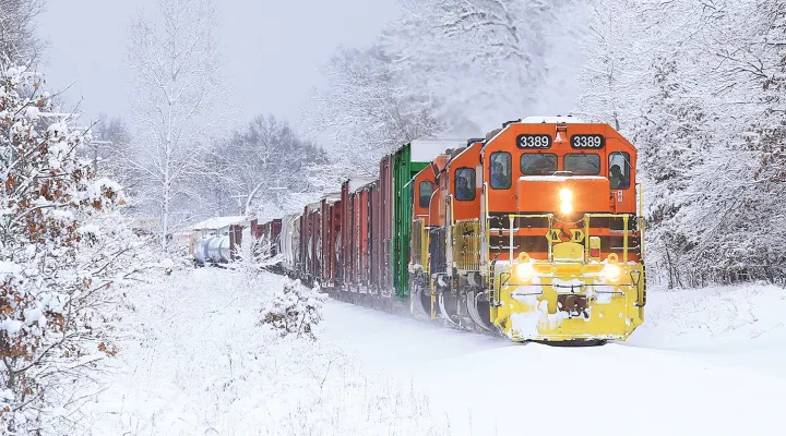 Train pulling freight railcars in a snowy landscape