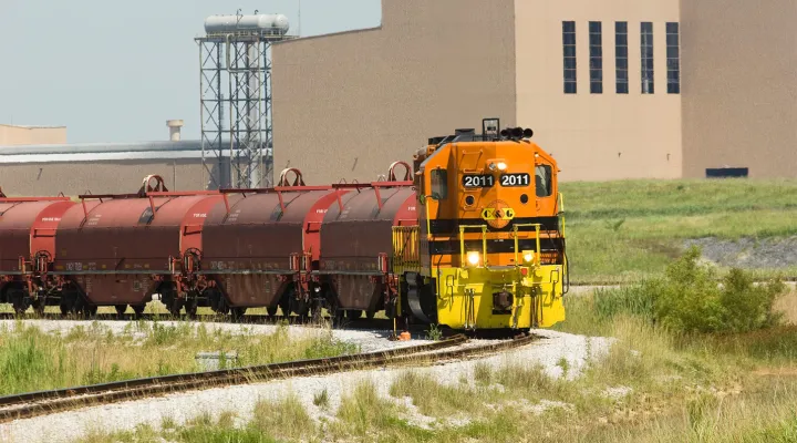 Train pulling tank cars near an industrial site