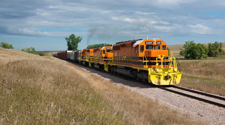 Train pulling freight railcars through a field